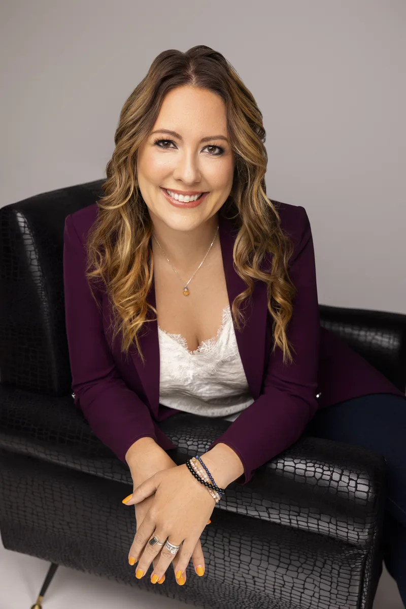 Kelly Pasztor, executive and leadership coach, smiling in a plum blazer